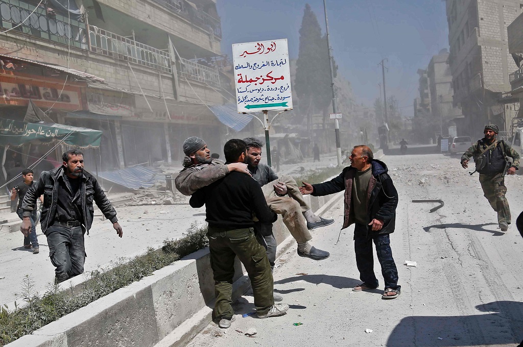 Warga menggendong seorang korban luka akibat serangan udara di Hamouria, Ghouta Timur di pinggiran Damaskus, Suriah, 3 April 2017. (Foto: AFP/ABDULMONAM EASSA)