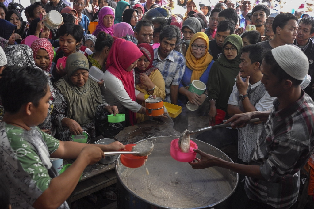 Warga antre mendapatkan bubur samin di Masjid Darussalam Jayengan. Antara Foto/Maulana Surya
