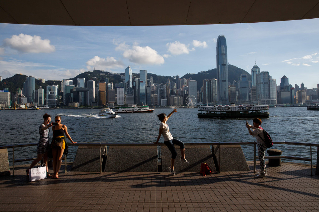 This file photo taken on June 24, 2016 shows tourists posing in front of Victoria Harbour with a view of the Hong Kong skyline in the background. (Photo:AFP/Anthony Wallace)