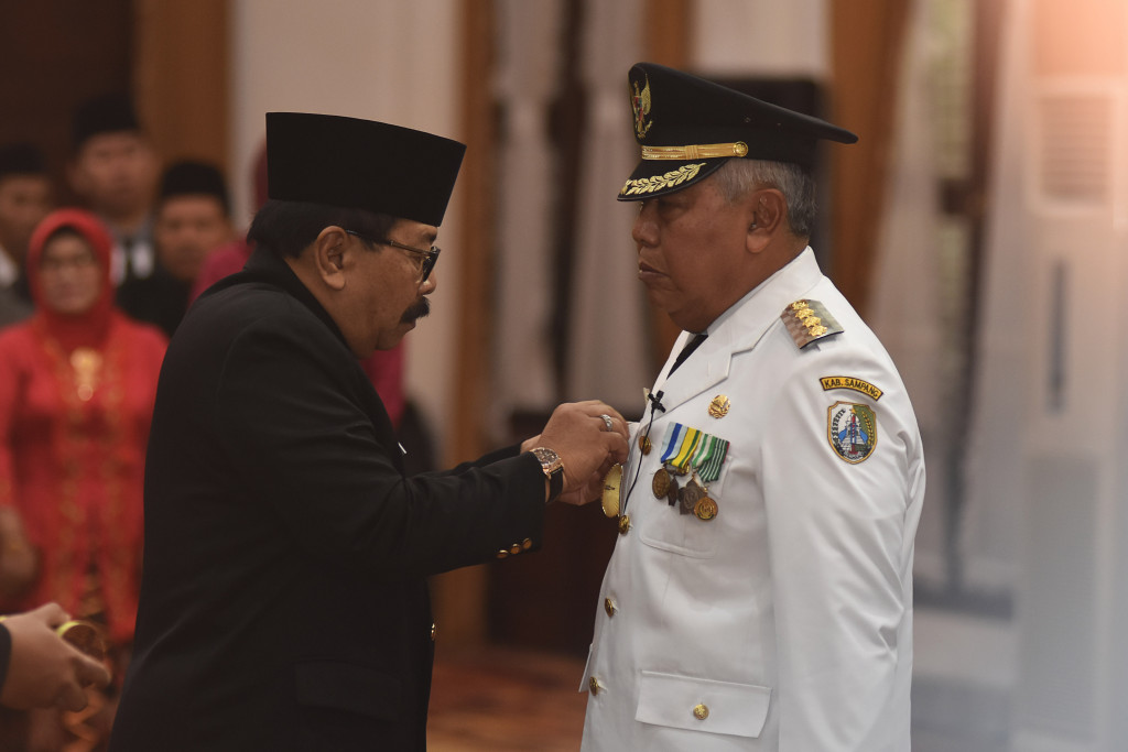 Gubernur Jatim Soekarwo (kiri) menyematkan tanda jabatan kepada Bupati Sampang Fadhilah Budiono (kanan) saat pelantikan di Gedung Negara Grahadi, Surabaya, Jatim, Kamis (6/7/2017). (Antara/M Risyal Hidayat)