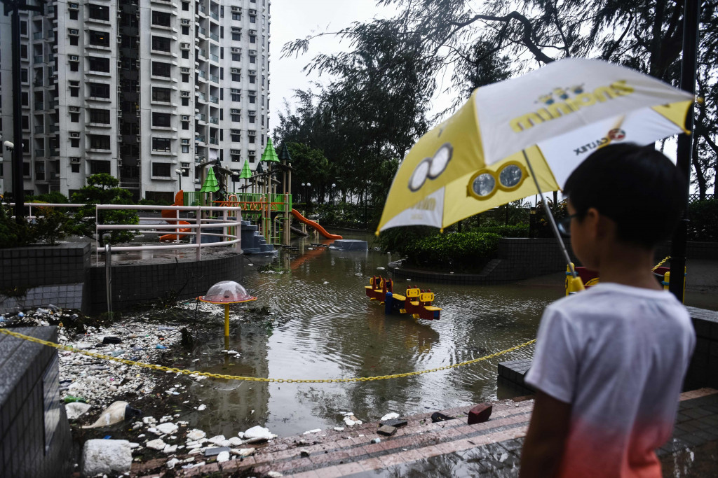 A young child looks at a flooded playground and marine debris after heavy winds and rains brought on by Typhoon Hato in Hong Kong on August 23, 2017. (Photo:AFP/Anthony Wallace)