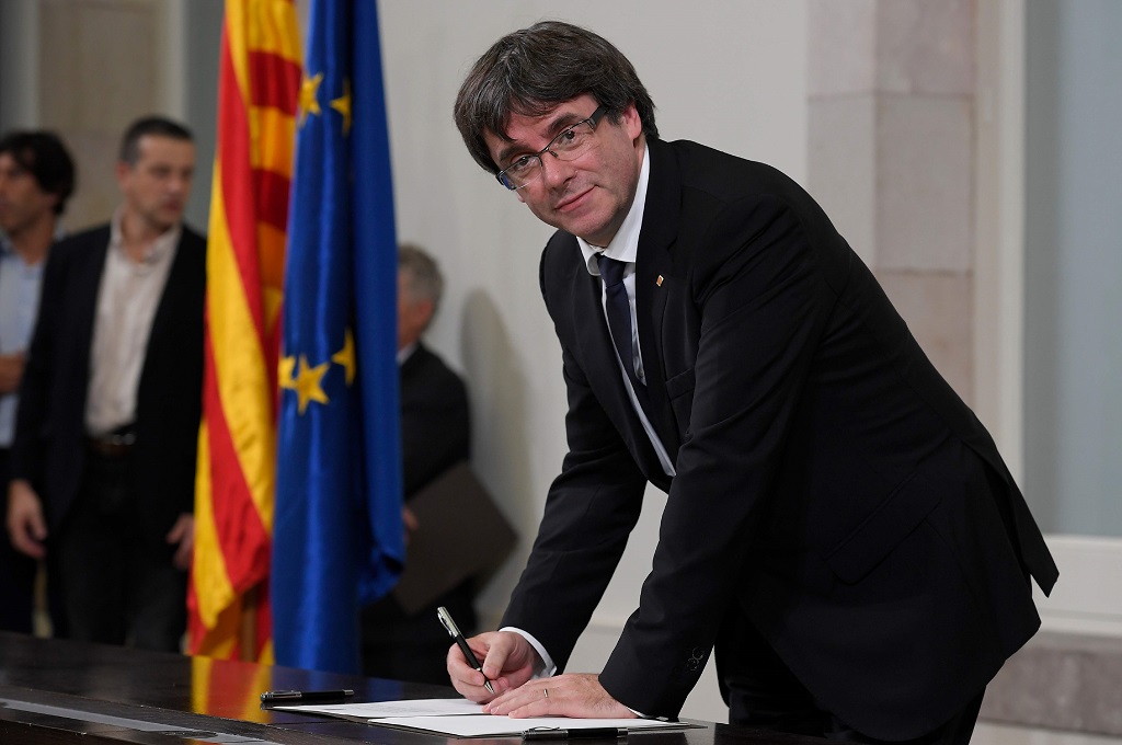 Presiden Regional Catalonia Carles Puigdemont menandatangani sebuah dokumen terkait referendum, 10 Oktober 2017. (Foto: AFP/LLUIS GENE)