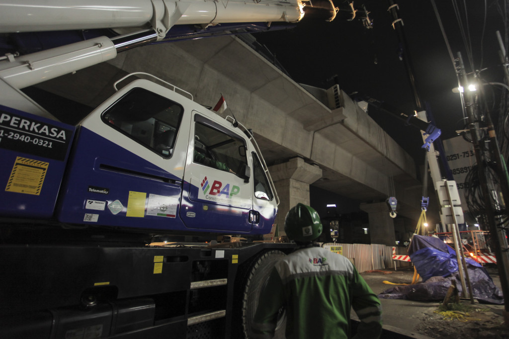 Petugas mengevakuasi pagar pembatas beton (parapet) yang jatuh ketika dilakukan pemasangan di atas deck girder proyek Mass Rapid Transit (MRT) di kawasan Panglima Polim, Jakarta, Jumat (3/11) malam. Foto: Antara/Muhammad Adimaja.