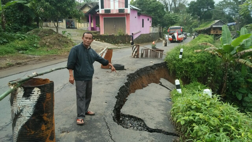Kasi Trantib Kecamatan Bawang, Suyatno menunjukkan jalan yang ambles akibat tergerus air bawah sungai dan diguyur hujan deras. Foto: Medcom.id/Iswahyudi