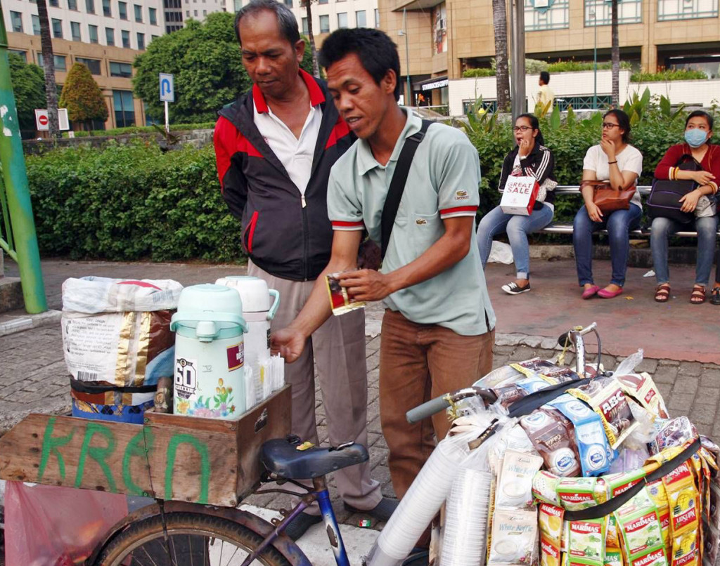 Ilustrasi seorang pedagang kopi keliling melayani pembeli di Jalan Asia Afrika, Jakarta, Minggu (20/9). MI/Galih Pradipta