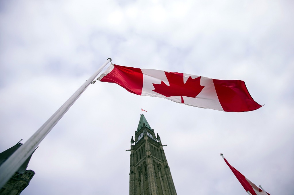 Bendera Kanada berkibar di depan menara gedung parlemen di Ottawa, 4 Desember 2015. (Foto: AFP/GEOFF ROBINS)