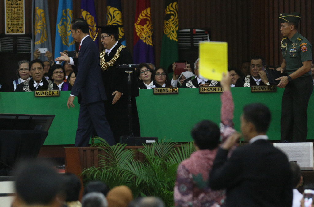 Mahasiswa UI berdiri dan mengacungkan kertas sebesar map berwarna kuning (kanan) ke arah Presiden Joko Widodo dan Rektor UI Prof Muhammad Anis. Foto: MI/Ramdani.