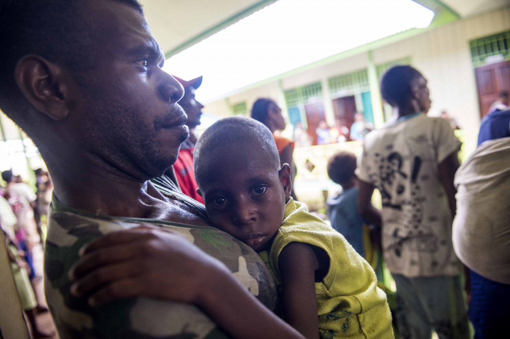 Ilustrasi: Warga menggendong anaknya saat menunggu antrean berobat di Puskesmas Ayam di Kampung Bayiwpinam, Distrik Akat, Kabupaten Asmat, Papua. Foto: Antara/M Agung Rajasa.