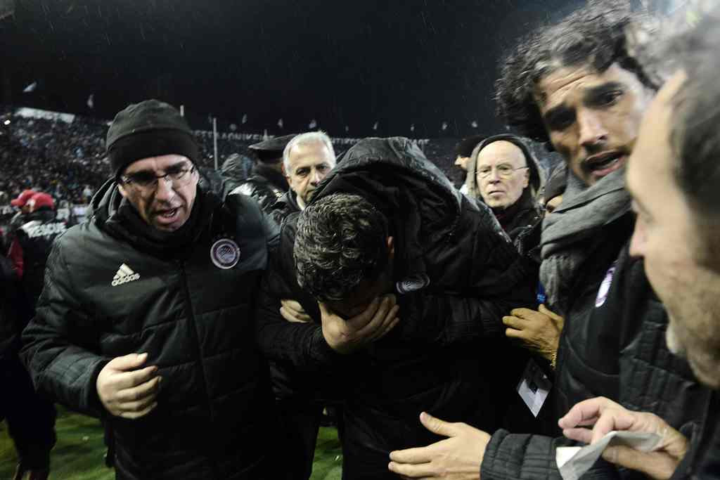 pelatih Olympiakos Oscar Garcia terkena lemparan gulungan kertas dari tribun penonton dan harus dibawa ke rumah sakit. (AFP PHOTO / SAKIS MITROLIDIS)