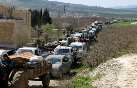 Syrian civilians ride their cars through Ain Dara in Syria's