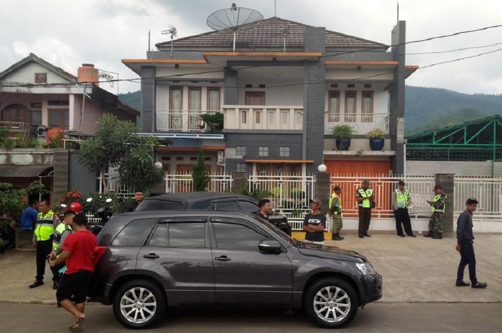 Polisi berjaga-jaga di depan rumah Syamsudin Simbolon, tempat memproduksi miras oplosan yang menewaskan puluhan warga Cicalengka, Kabupaten Bandung, Medcom.id - Octa