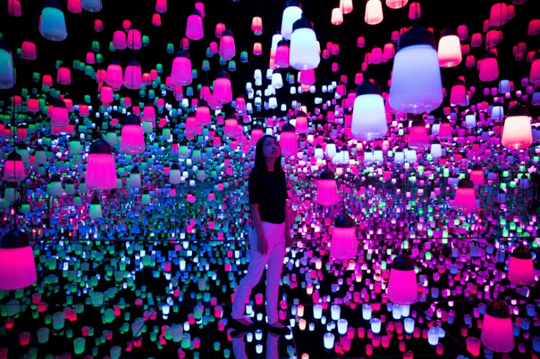 A member of the teamLab collective walks through a digital installation room in Tokyo featuring hanging lamps that light up as the visitor nears. (Photo:AFP/Behrouz Mehri)