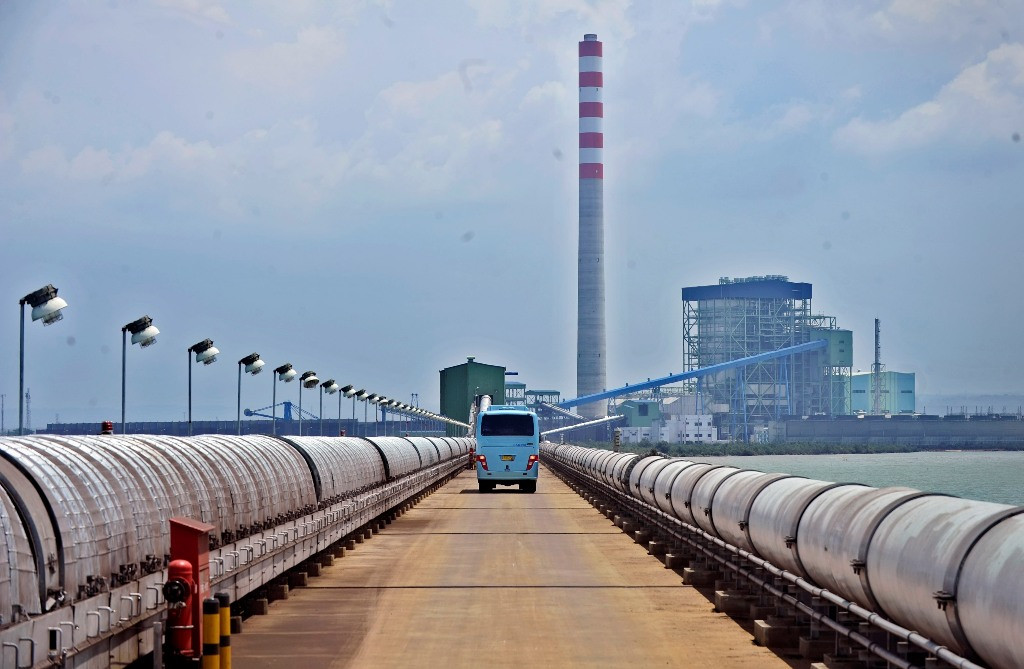 Sebuah bus melintas di dekat instalasi PLTU Cirebon yang menghasikan 1 x 660 mw, di Cirebon, Jawa Barat. (Foto: Antara/Yudhi Mahatma).