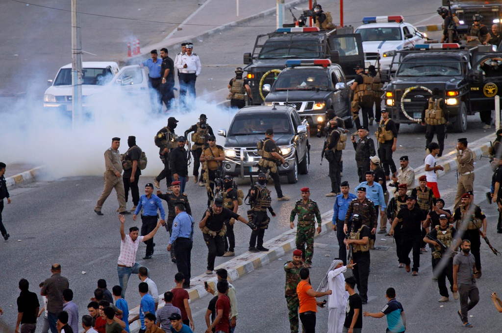 Warga bentrok dengan petugas keamanan dalam demo memprotes kemiskinan di kota Najaf, Irak selatan, 14 Juli 2018. (Foto: AFP/HAIDAR HAMDANI)