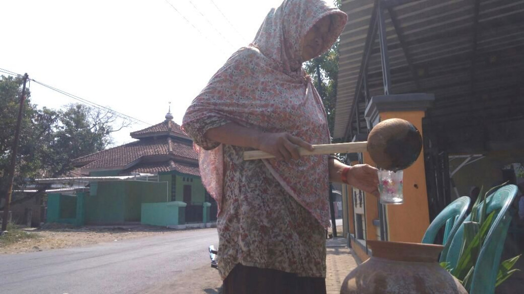 Seorang warga meminum air dari gentong yang disediakan keluarga calon haji di Cirebon/Medcom.id/Ahmad Rofahan