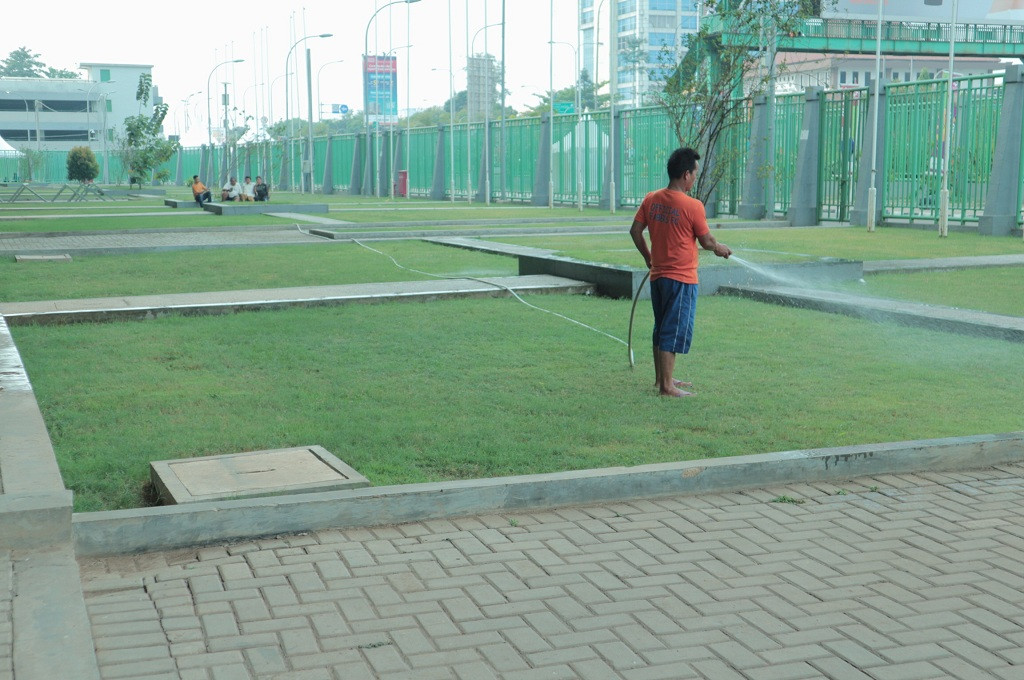 Seorang petugas tengah menyiram taman di bagian depan Stadion Patriot Candrabaga, Kota Bekasi, Medcom.id - Antonio