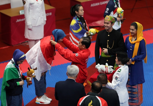 Presiden Joko Widodo mengalungkan medali emas kepada Defia, penyumbang medali emas pertama untuk Indonesia/MI/Ramdani