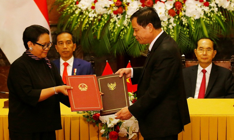  Presiden Vietnam Tran Dai Quang (kanan belakang) menyaksikan kesepakatan Menlu Retno Marsudi dengan Menteri Agrikultur Nguyen Xuan Cong. (Foto: AFP).