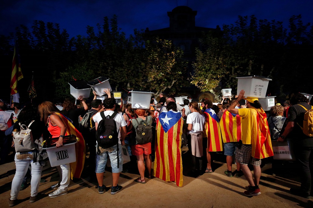 Demonstran membawa kotak surat yang digunakan dalam referendum Catalonia setahun lalu saat berunjuk rasa di Barcelona, Spanyol, 1 Oktober 2018. (Foto: AFP/PAU BARRENA)