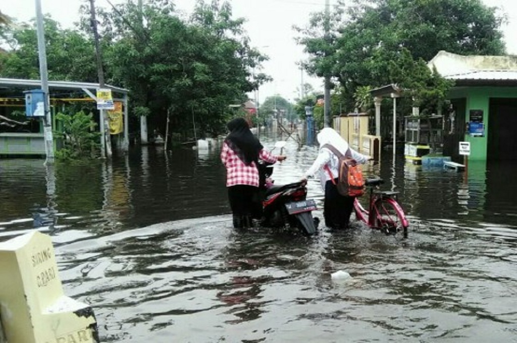 Warga mendorong sepeda motor lantaran terjebak banjir di Sidoarjo, November 2017, Medcom.id - Syaikhul Hadi