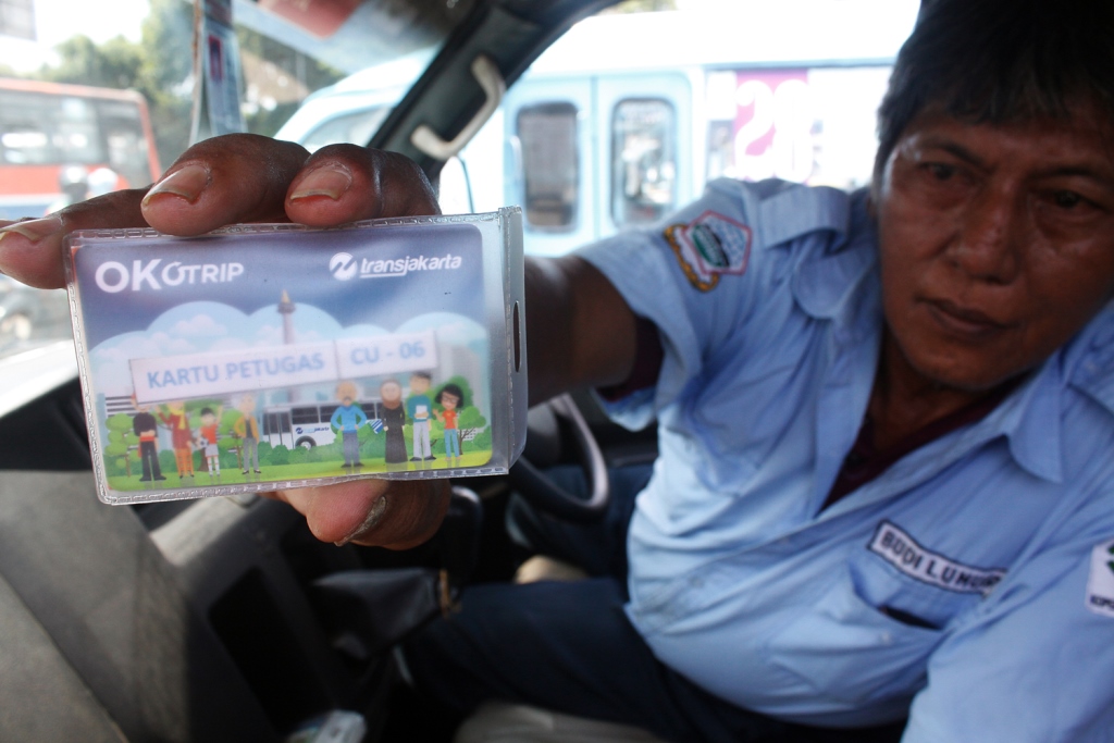 Supir Angkot Ok Otrip (kini beralih nama menjadi Jak Lingko) menunjukkan kartu OK Otrip saat menunggu penumpang di Terminal Kampung Melayu, Jakarta. MI/Barry Fathahilah.