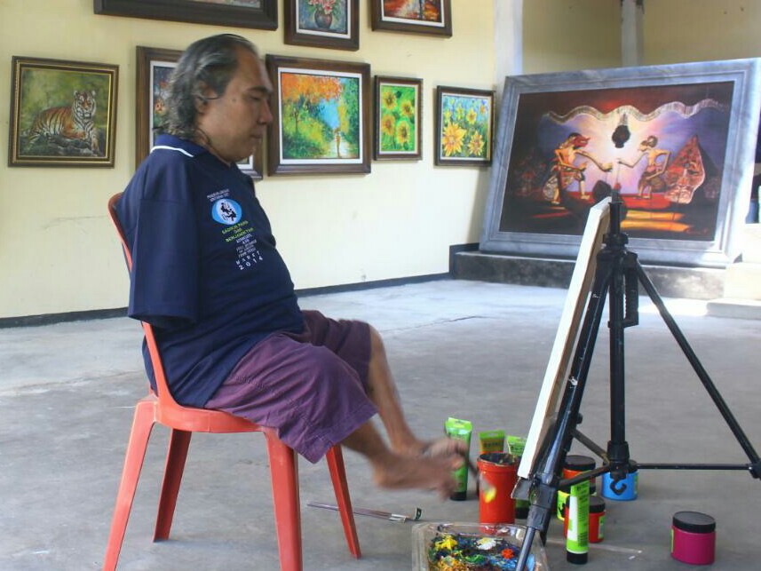 Sadikin Pard, pelukis tunadaksa, saat melukis di padepokannya, Selasa 16 Oktober 2018. Medcom.id/Daviq Umar Al Faruq