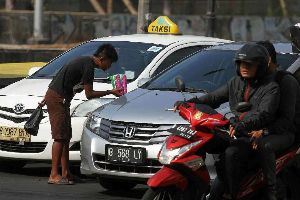 Seorang anak menawarkan tisu dagangannya kepada para pengendara di perempatan jalan, MI/Arya Manggala.