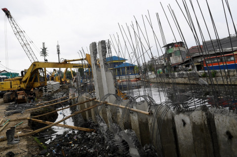 Pekerja menggunakan alat berat menyelesaikan pemasangan dinding