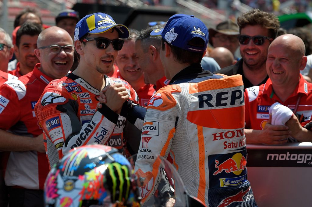 Jorge Lorenzo dan Marc Marquez berjabat tangan usai sama-sama naik podium pada MotoGP Barcelona 2018 (Foto: AFP PHOTO / LLUIS GENE)