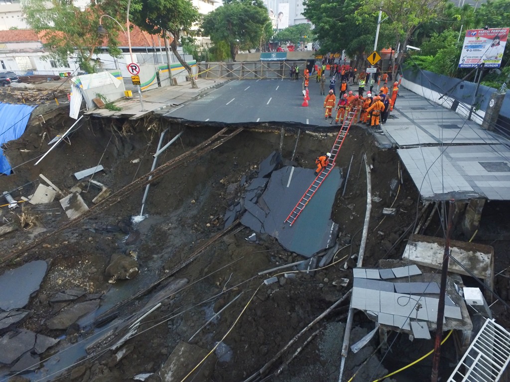 Sejumlah petugas pemadam kebakaran memeriksa kondisi tanah ambles di Jalan Raya Gubeng, Surabaya, Jawa Timur. (Foto: ANTARA/Didik Suhartono)