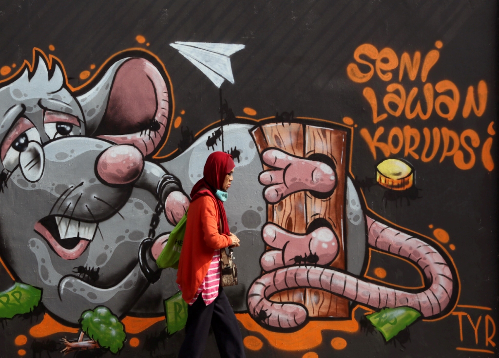 Warga melintas mural melawan korupsi di kawasan Kebon Nanas, Grogol Utara, Kebayoran Lama, Jakarta Selatan. Foto: MI/Ramdani.