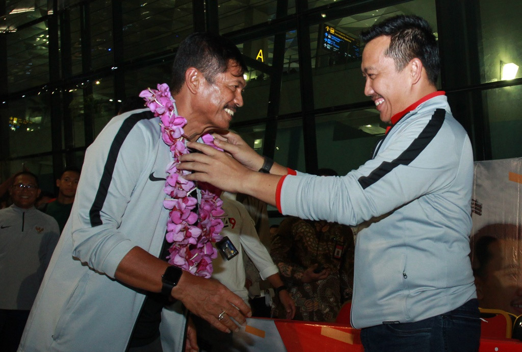 Menpora Imam Nahrawi (kanan) mengalungkan bunga kepada pelatih kepala Timnas U 22 Indra Sjafri (kiri) setibanya di Bandara Soekarno Hatta, Tangerang. (Foto: Antara/Muhammad Iqbal)