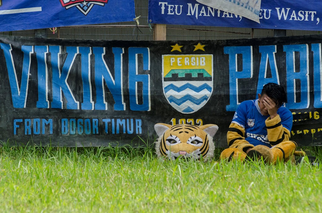 Suporter yang menjadi Simba, Maskot Persib Bandung duduk termenung usai pertandingan Persib. (ANTARA FOTO/Novrian Arbi) 