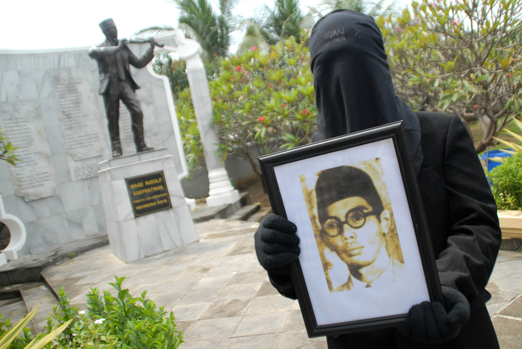 Seorang seniman membawa potret dari Wage Rudolf Supratman dalam teatrikal ketika berziarah di Makam WR Soepratman, Surabaya. (Foto: ANTARA FOTO/M Risyal Hidayat)