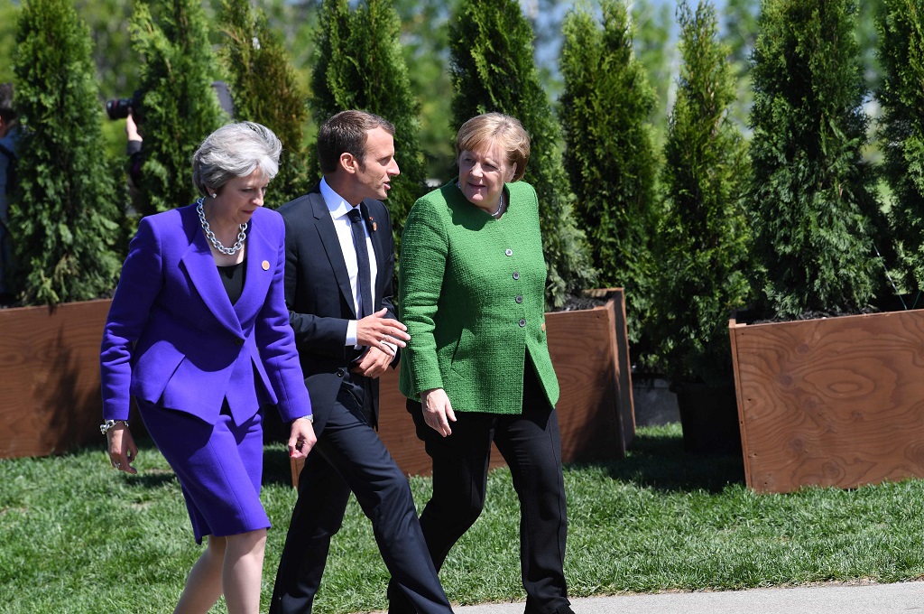 PM Inggris Theresa May (kiri), Presiden Prancis Emmanuel Macron (tengah) dan Kanselir Jerman Angela Merkel dalam sebuah acara di Kanada, 8 Juni 2018. (Foto: AFP/SAUL LOEB)