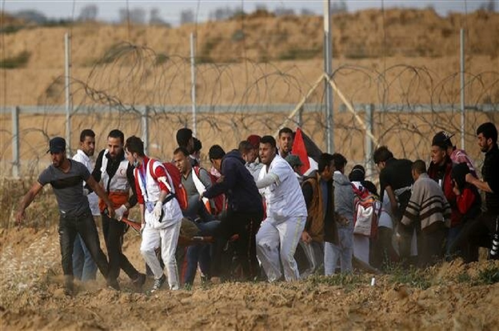 Petugas medis dan demonstran mengangkut seseorang yang terluka dalam bentrokan di perbatasan Gaza dan Israel, 26 April 2019. (Foto: AFP)
