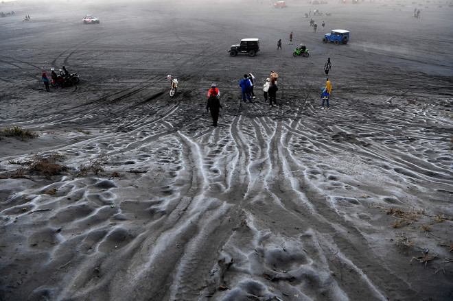 Pengunjung melintas di hamparan pasir yang diselimuti empun upas di kawasan Gunung Bromo, Probolinggo, Jawa Timur.