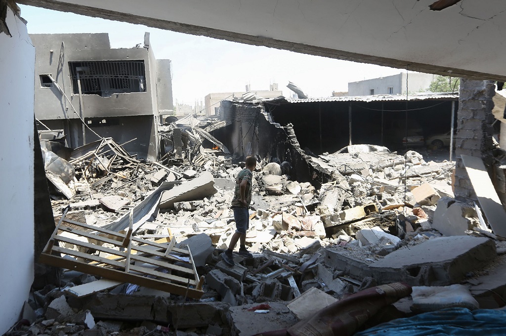 Seorang pejuang GNA memeriksa reruntuhan bangunan di kompleks militer Yarmouk, Libya, 1 Juli 2019. (Foto: AFP/MAHMUD TURKIA)