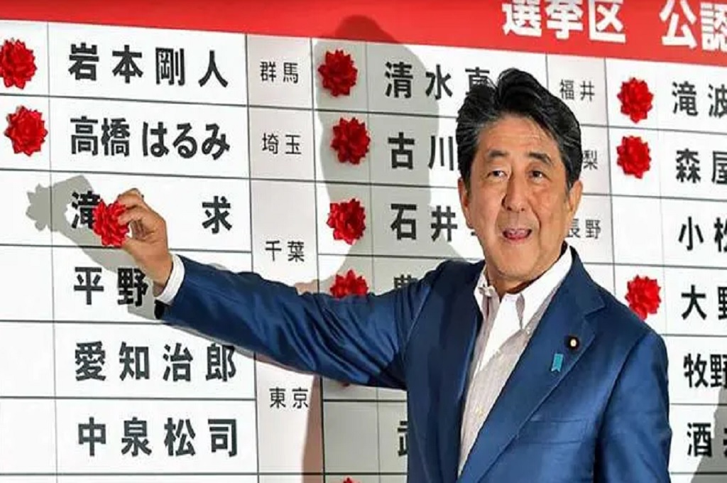 Berlokasi di markas LDP di Tokyo, PM Abe meletakkan bunga kertas di samping nama kandidat yang menang dalam pemilihan umum Majelis Tinggi Jepang, Minggu 21 Juli 2019. (Foto: Kazuhiro NOGI/AFP)