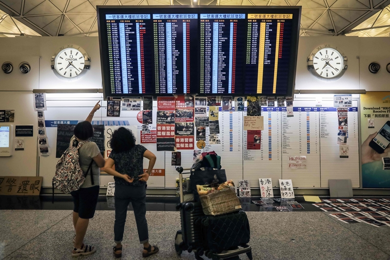 Calon penumpang di Bandara Hong Kong melihat papan pengumuman keberangkatan. Foto: AFP.