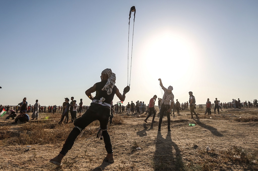 Demonstran Palestina menggunakan ketapel dalam menghadapi pasukan Israel di dekat pagar perbatasan yang memisahkan Jalur Gaza dengan Israel, Jumat 16 Agustus 2019. (Foto: AFP/MAHMUD HAMS)