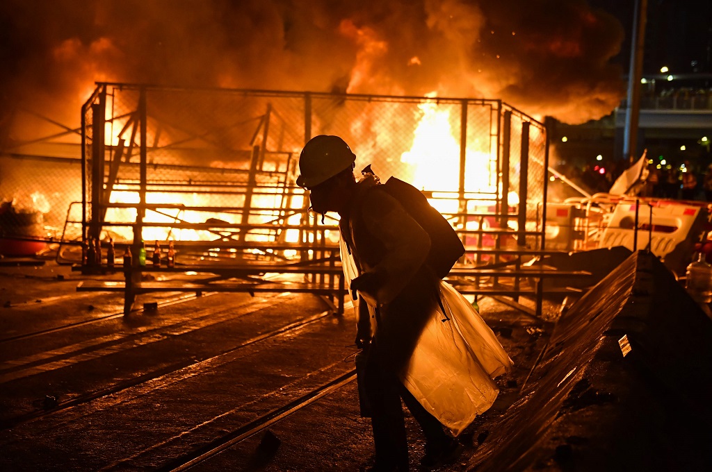 Seorang pengunjuk rasa berjalan melewati barikade yang terbakar di distrik Wan Chai, Hong Kong, Sabtu 31 Agustus 2019. (Foto: AFP/LILLIAN SUWANRUMPHA)