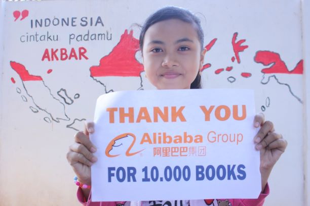 Seorang siswa memegang kertas bertuliskan ucapan terima kasih kepada UCWeb atas donasi 10.000 bukunya.  Foto/Dok UCWeb.