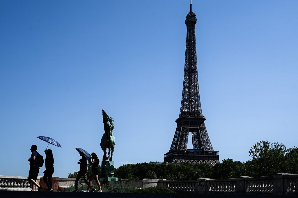 Turis menggunakan payung di tengah terik matahari di Paris, Prancis, 23 Juli 2019. (Foto: AFP/PHILIPPE LOPEZ)