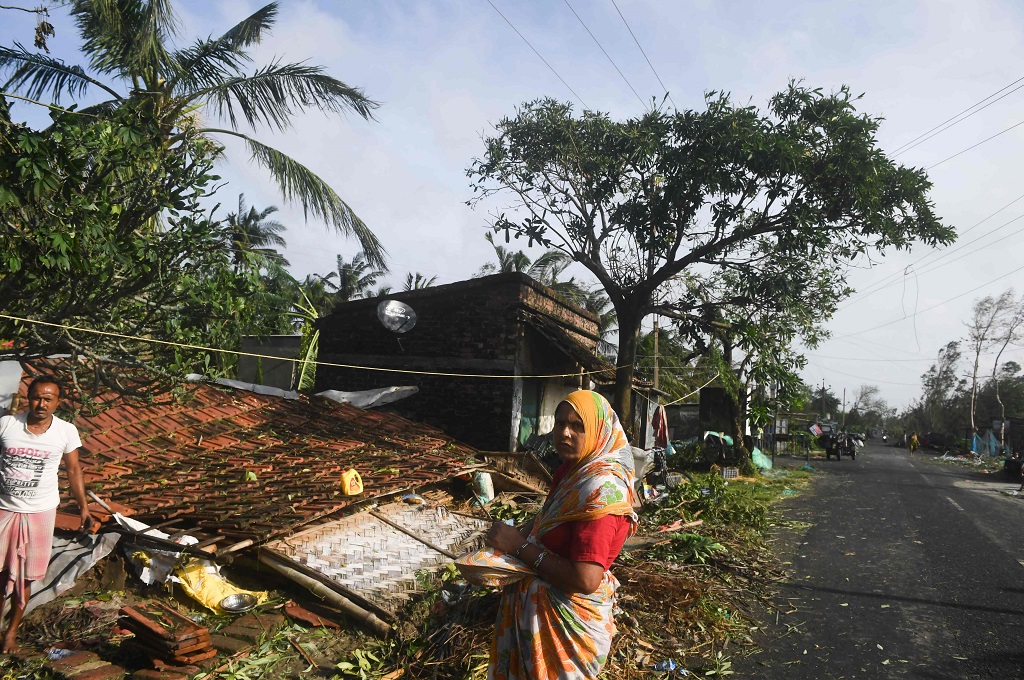 Warga berada di dekat sebuah rumah yang roboh usai diterjang Siklon Bulbul di Bakkhali, India, 10 November 2019. (Foto: AFP/DIBYANGSHU SARKAR)