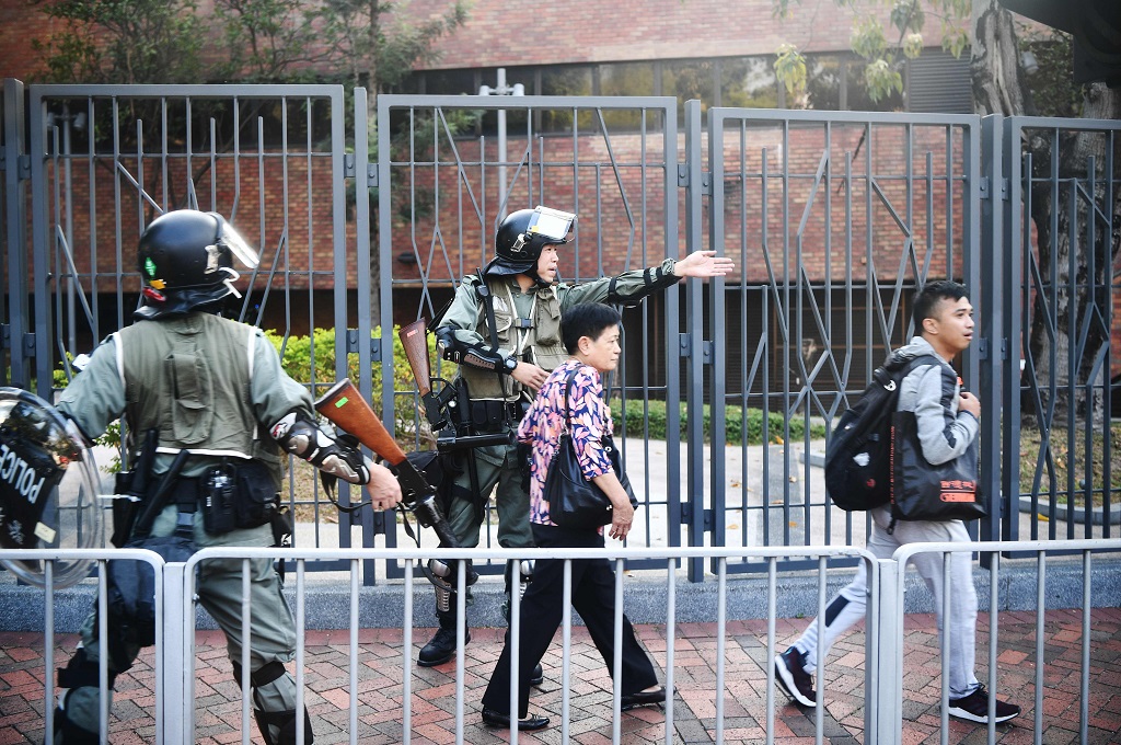 Polisi mengarahkan warga untuk mengambil rute lain di tengah aksi blokade jalan raya oleh demonstran di Hong Kong, Senin 11 November 2019. (Foto: AFP/ANTHONY WALLACE)