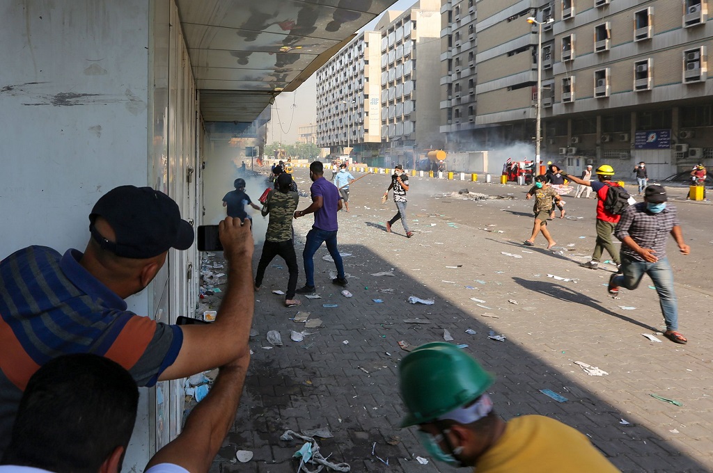 Demonstran berlari dari tembakan gas air mata di Baghdad, Irak, Minggu 10 November 2019. (Foto: AFP/SABAH ARAR)