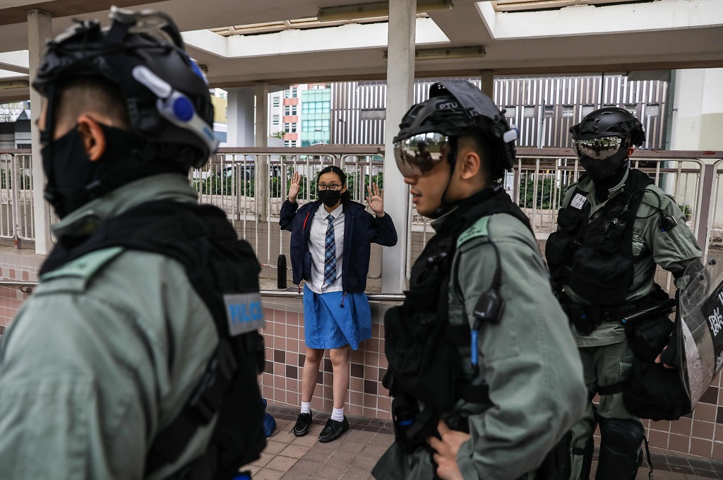 Seorang siswi sekolah menengah mengangkat kedua tangan di hadapan polisi di distrik Sai Wan Ho, Hong Kong, 11 November 2019. (Foto: AFP/DALE DE LA REY)