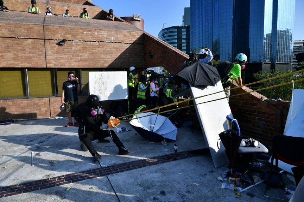 Demonstran di kampus Polytechnic University Hong Kong menggunakan katapul untuk melontarkan batu bata ke arah polisi, Minggu 17 November 2019. (Foto: AFP Photo/Anthony WALLACE)