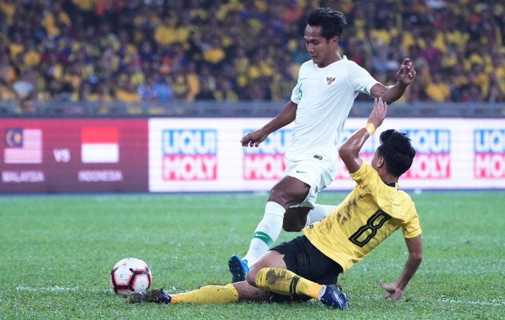 Aksi gelandang Indonesia Hendro Siswanto (atas) diadang gelandang Malaysia Nor Azam Azih (bawah) (Foto: AFP)